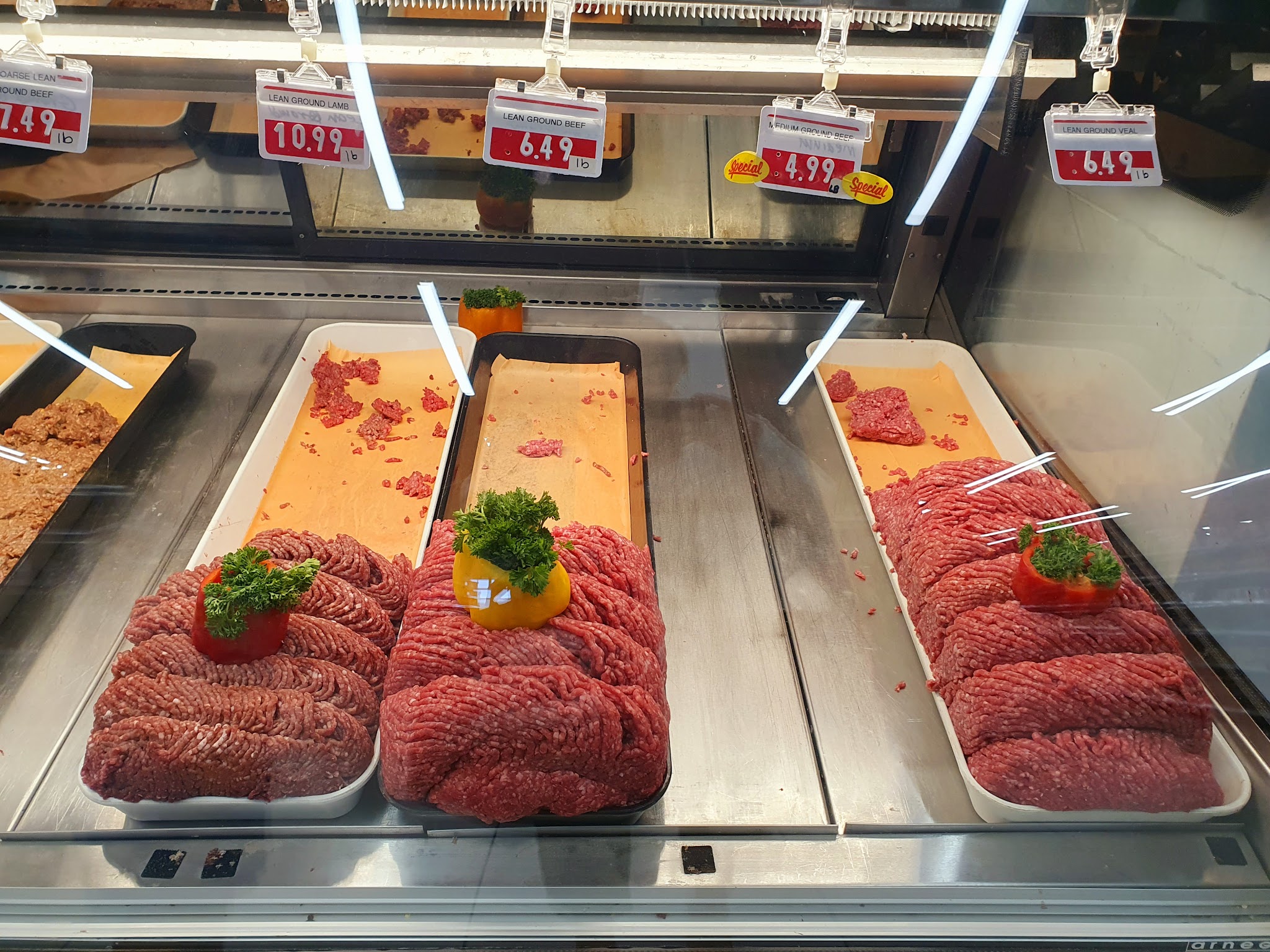 Fresh halal ground beef and meats displayed at the Kabul Farms butcher counter with price tags