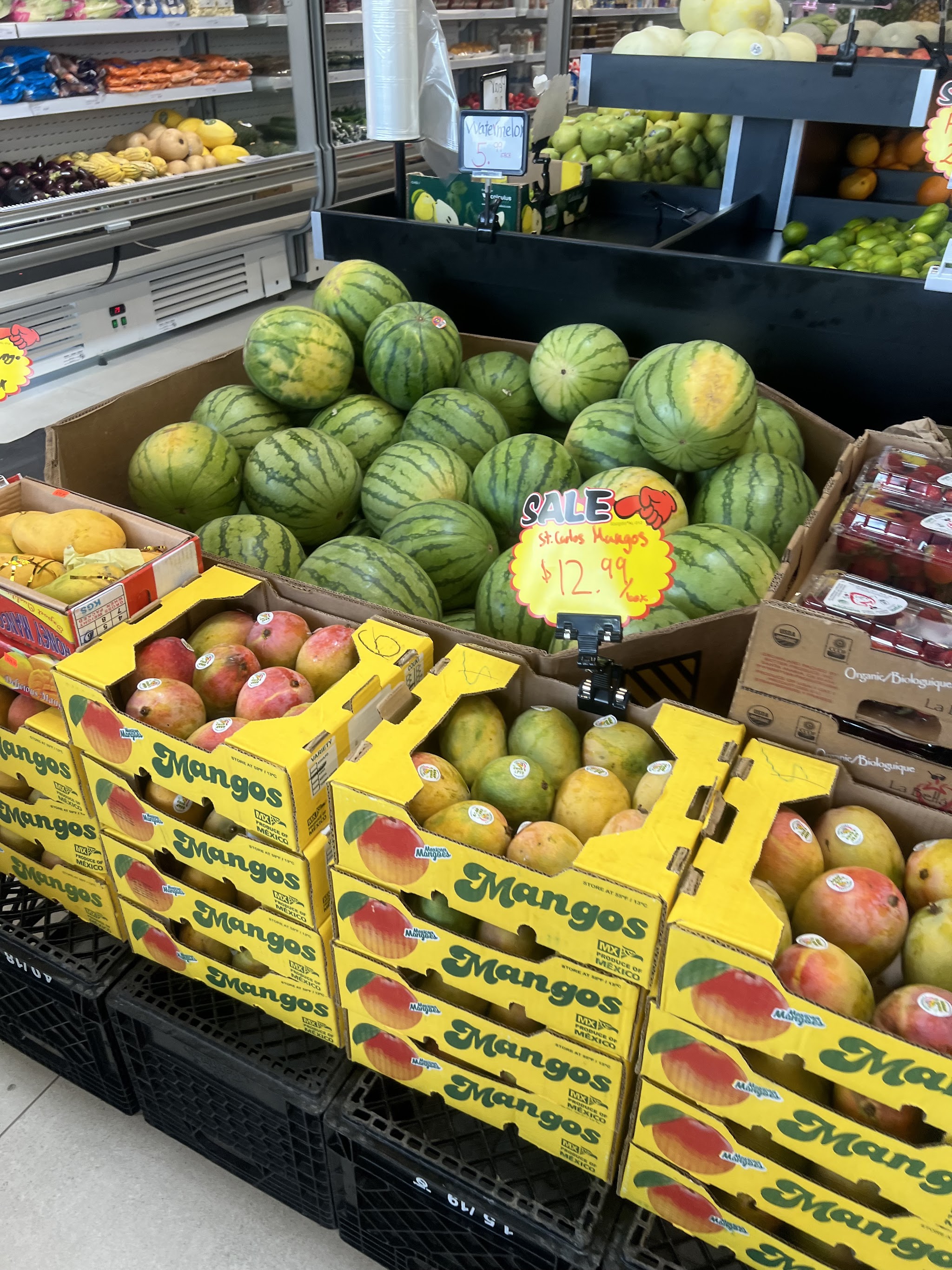 Fresh produce display at Kabul Farms with watermelons, mangoes, and seasonal fruits