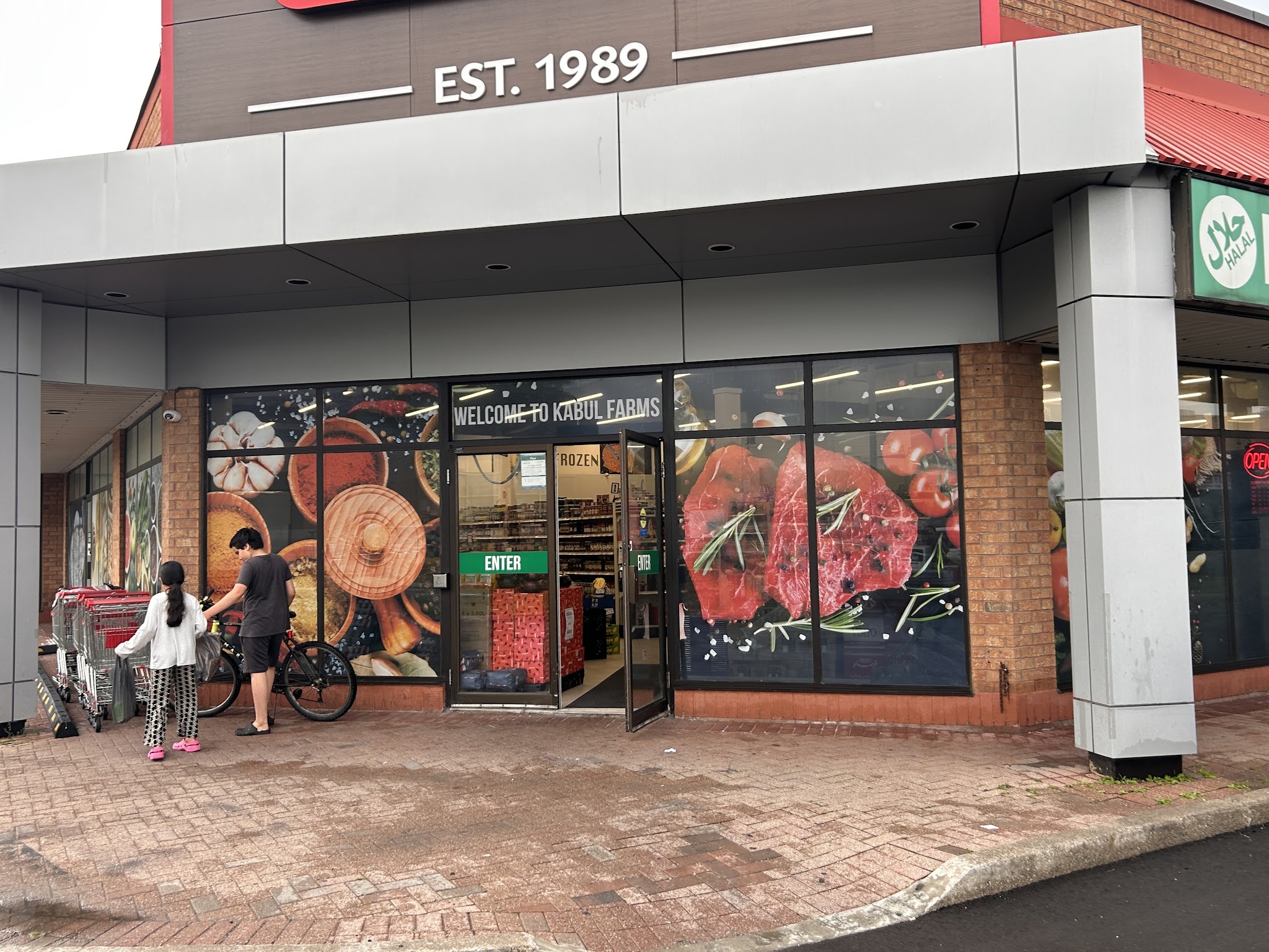 Kabul Farms Supermarket daytime storefront showing EST. 1989 and Welcome to Kabul Farms signage
