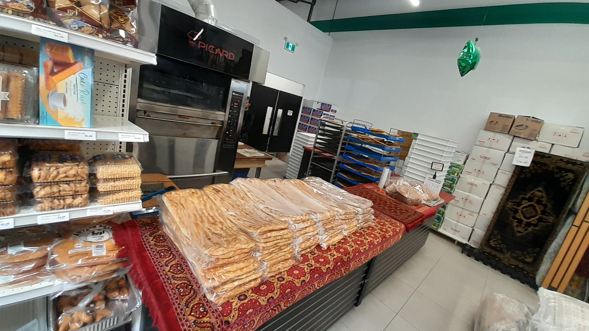 Freshly baked Afghan bread (Naan-e Afghani) stacked in the Kabul Farms bakery section with ovens visible