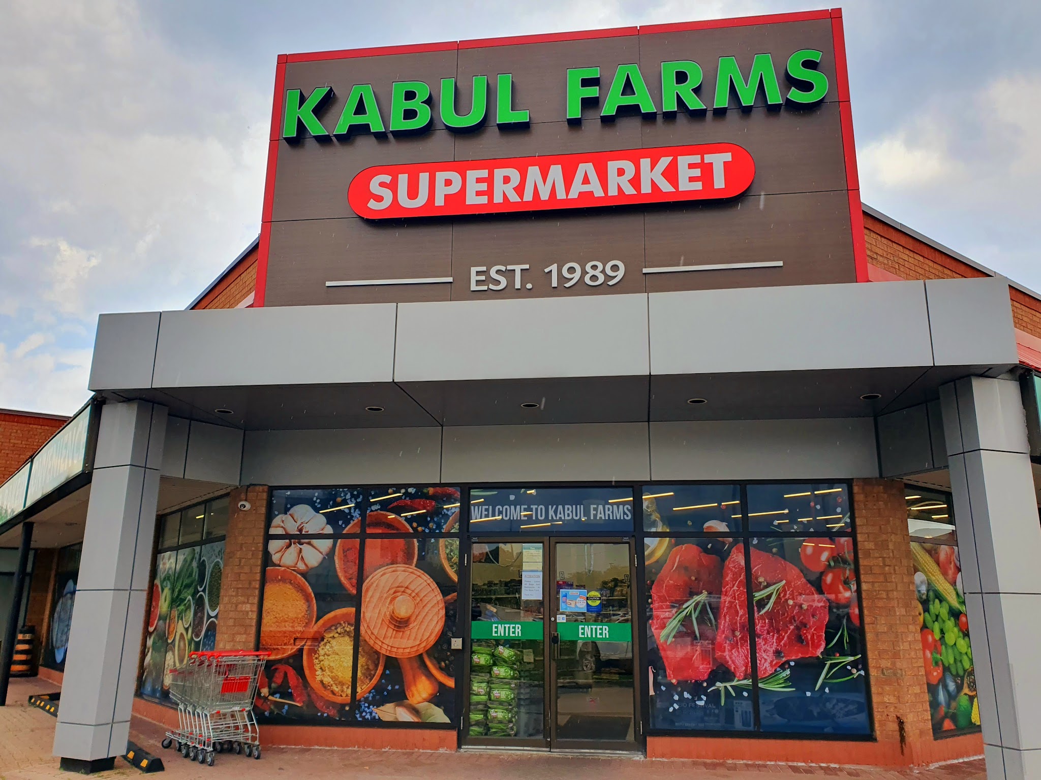 Kabul Farms Supermarket storefront with colorful window wraps showing fresh produce and meats